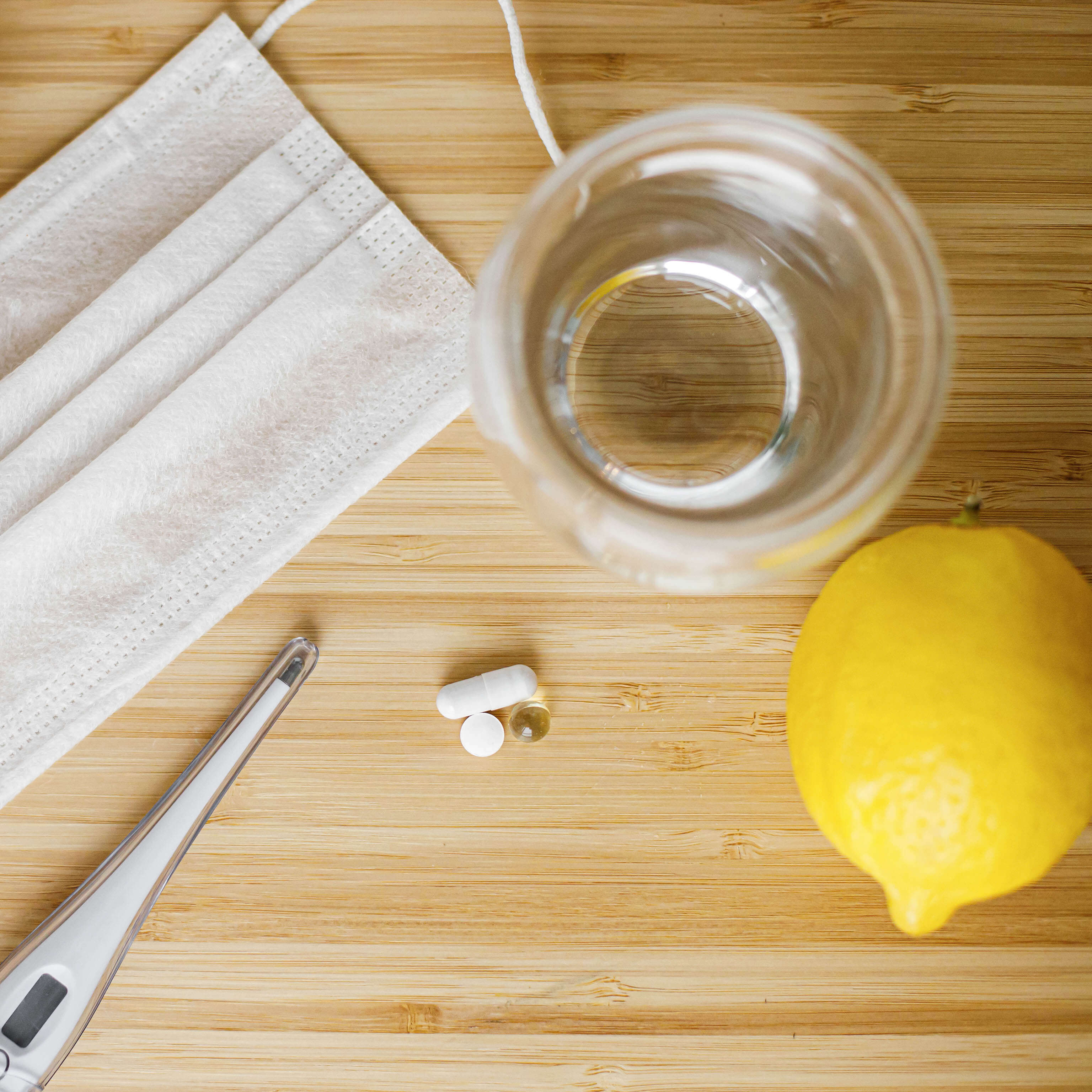 Zitrone neben einem Glas Wasser, Tabletten und einer Atemmaske